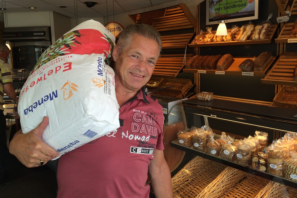 Bakker Ad Otto uit Ter Aar draagt voor de laatste keer een zak meel, voordat hij met pensioen gaat. Foto Leidsch Dagblad