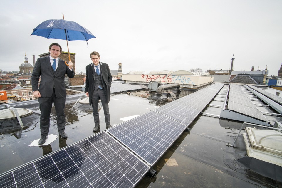 Max Grapperhaus (met paraplu) en Frank van der Wal op het zonnedak van Minerva. ,,We besparen dik tien procent op de energierekening.'' Foto Hielco Kuipers