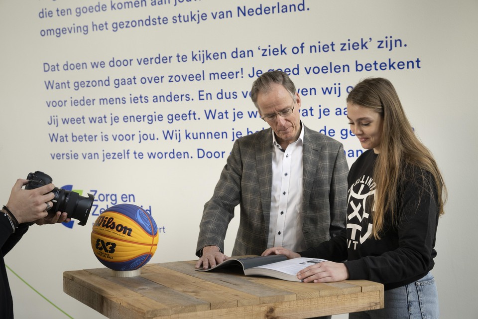 Henk Gerla, directeur van Zorg en Zekerheid, overhandigt het eerste exemplaar aan de Katwijkse basketbalster Alissa van der Plas.