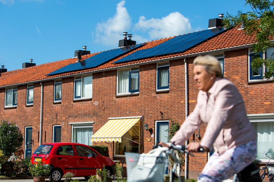 Een fietser rijdt voorbij een Woonforte-woning met zonnepanelen.