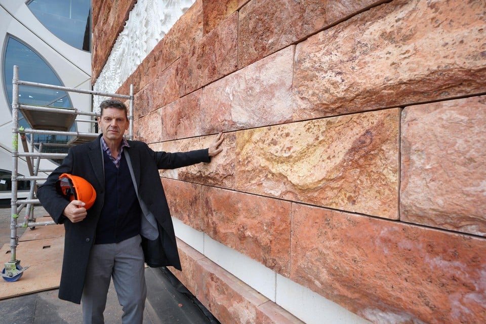 Directeur Edwin van Huis bij een muur van Iraans natuursteen.