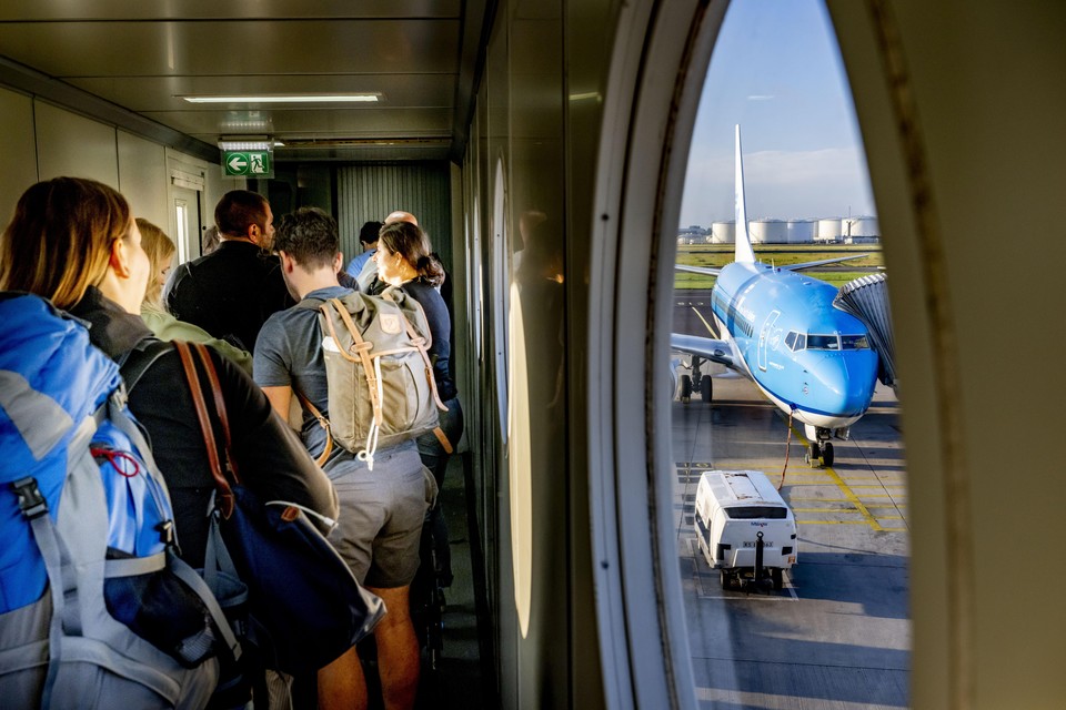 Reizigers staan te wachten bij een KLM-toestel op Schiphol.