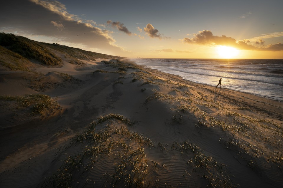 Een hardloper op het smalle strookje plat strand dat is overgebleven ten zuiden van Katwijk, doordat zich in razend tempo nieuwe duinen hebben gevormd.