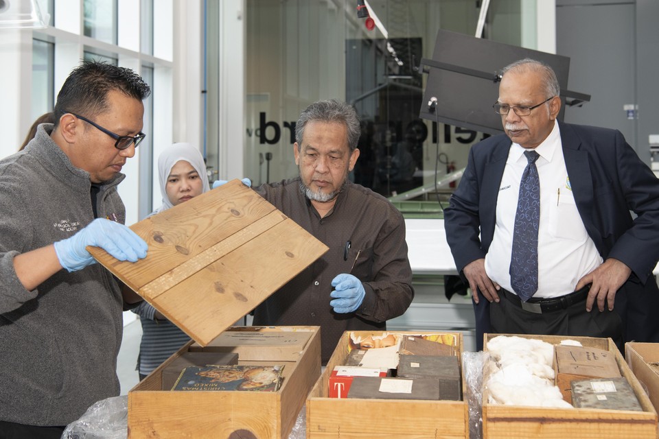 Archeologen Mokhtar Saidin (midden) en Shaiful Shahidan openen de doos en kisten met skeletmateriaal, onder toeziend oog van vertegenwoordiger van de deelstaat Penang.