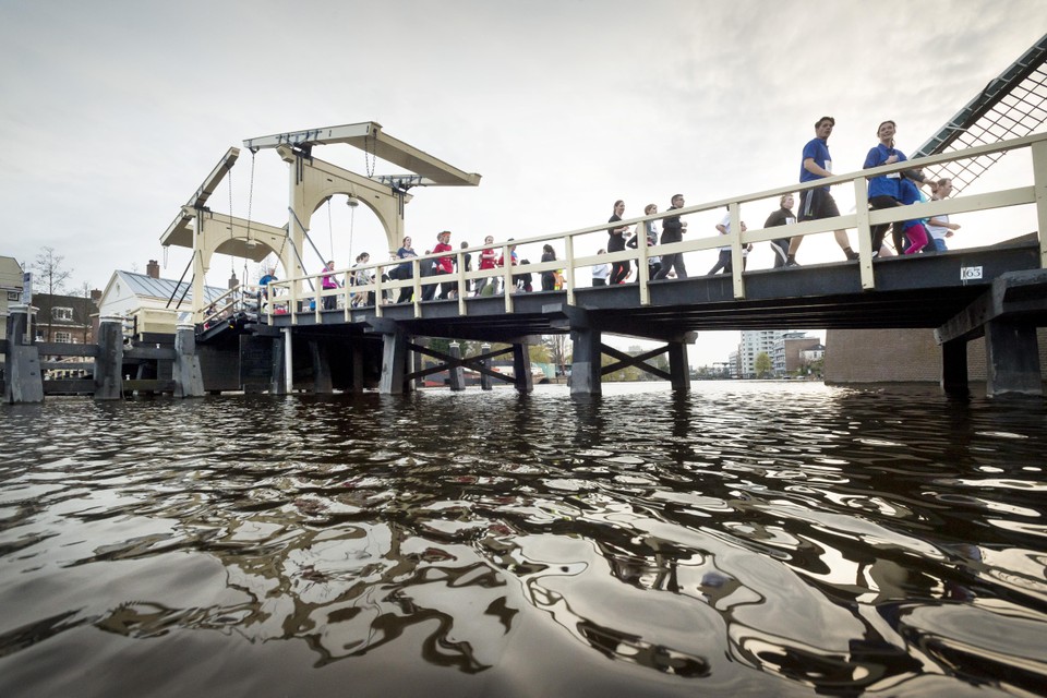 Terwijl de avond valt over het Galgewater, stromen de deelnemers aan de Singelloop over de Rembrandtbrug.