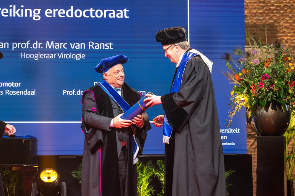 Decaan Pancras Hogendoorn van de Leidse Faculteit Geneeskunde (r) overhandigt Marc Van Ranst de koker met daarin de bul.