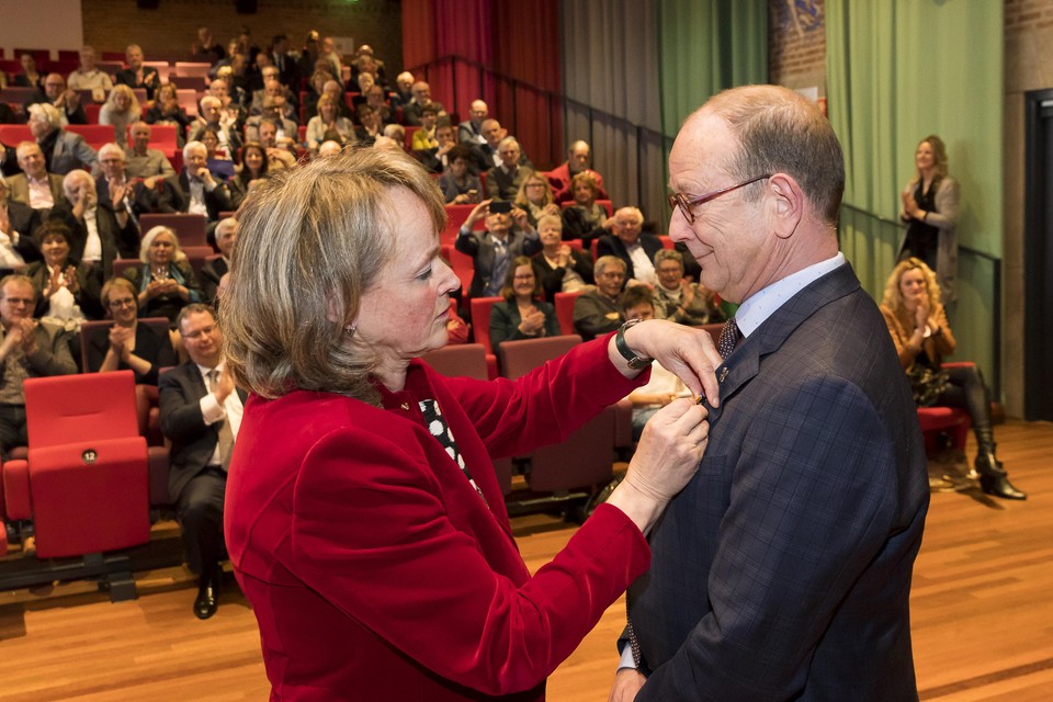 Burgemeester Lies Spruit speldt Adri de Roon de koninklijke medaille op.