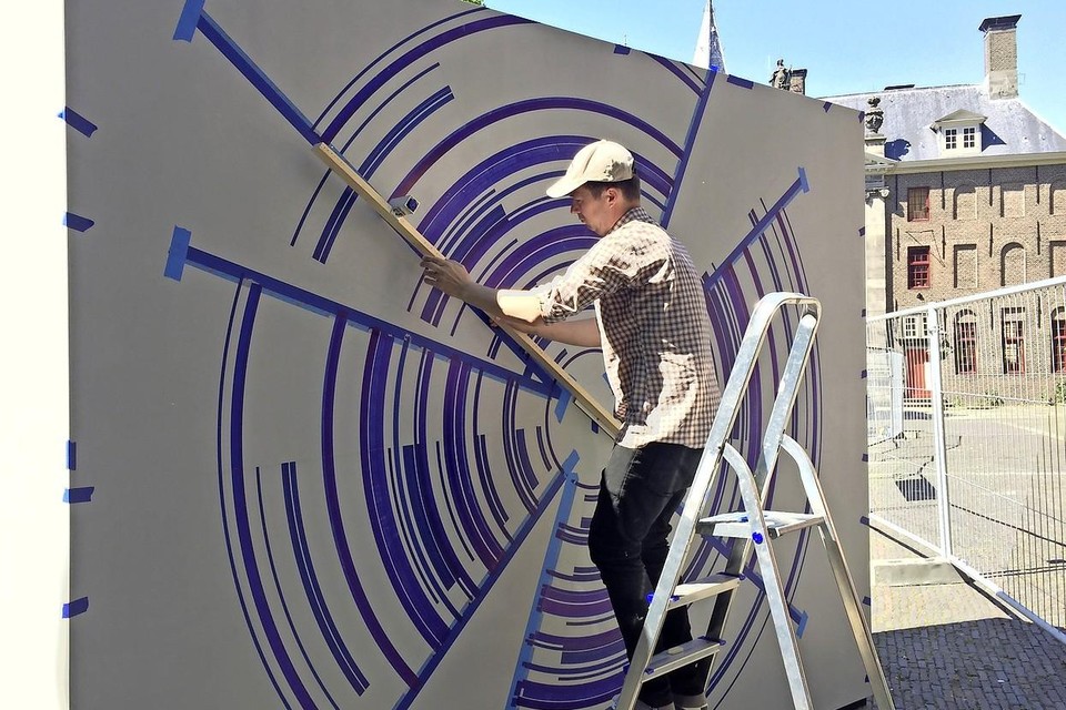 De Australische kunstenaar Justin Andrews werkt geconcentreerd aan zijn wandschildering ’Towards zero II’.
