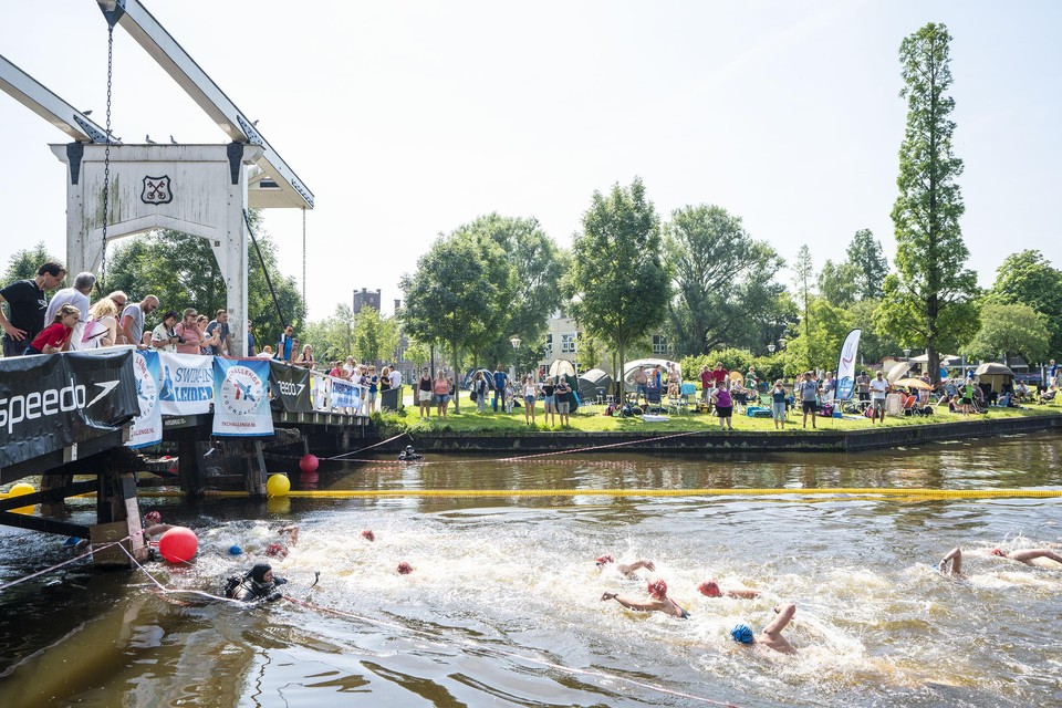 Toeschouwers moedigen de zwemmers vanaf de brug bij het Huigpark aan.