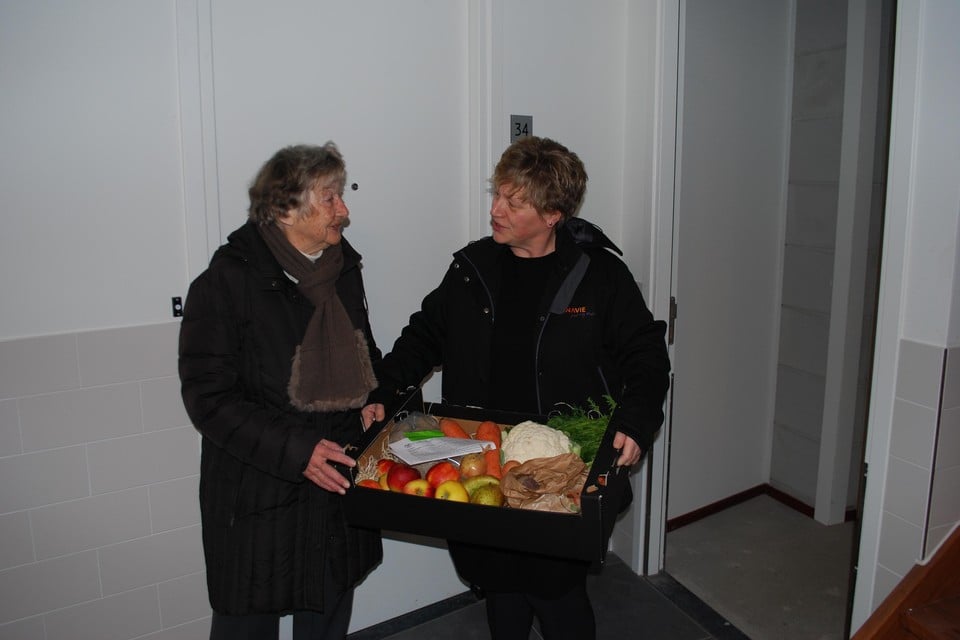 Verhuurmakelaar Anita Dekker van Dunavie overhandigt de eerste sleutel aan mevrouw Valk, inclusief een mand met groente en fruit.