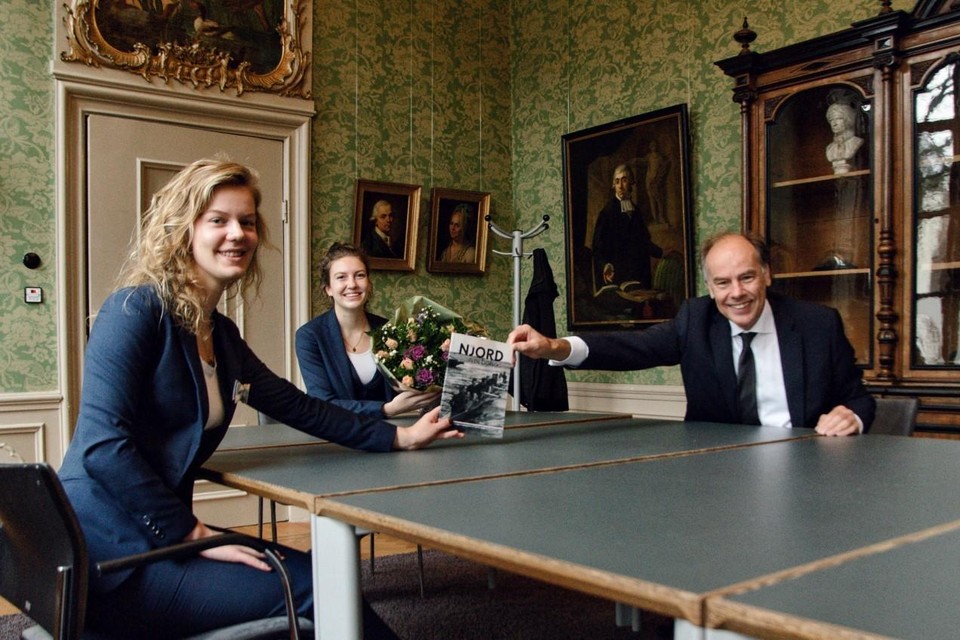 Njord-praeses Rosalie ten Wolde (links) en Ab Actis Julia van Sluijs overhandigen het eerste exemplaar van ’Njord in de oorlog’ aan rector magnificus Carel Stolker.